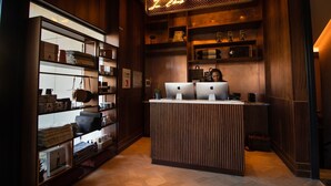 A reception desk with two Apple iMac computers, wooden shelving with various items, and a neon sign above.