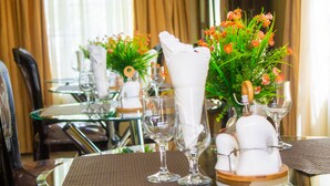 Una mesa de comedor dispuesta con cristalería, servilletas y centros de mesa florales.