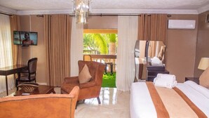 Habitación de hotel con cama, escritorio, silla, televisor y vistas al exterior.
