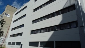 En byggnad med flera våningar och en modern arkitektonisk design, med en rad fönster och en tydligt markerad entré.