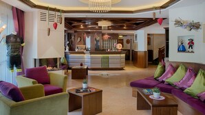 Eine Hotelhalle mit Empfangstresen, einer Sitzecke und einem Chandelier.