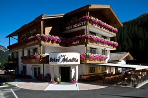 Een hotel met een restaurant op de tweede verdieping, omgeven door bergen.