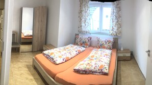 A narrow room with a bed, a window with curtains, and a door. - Hotel Gasthof Ratstube (Kirchheim unter Teck)