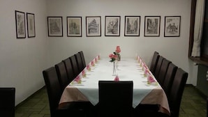 A conference room with a long table, chairs, framed pictures on the wall, and a tiled floor. - Hotel Gasthof Ratstube (Kirchheim unter Teck)