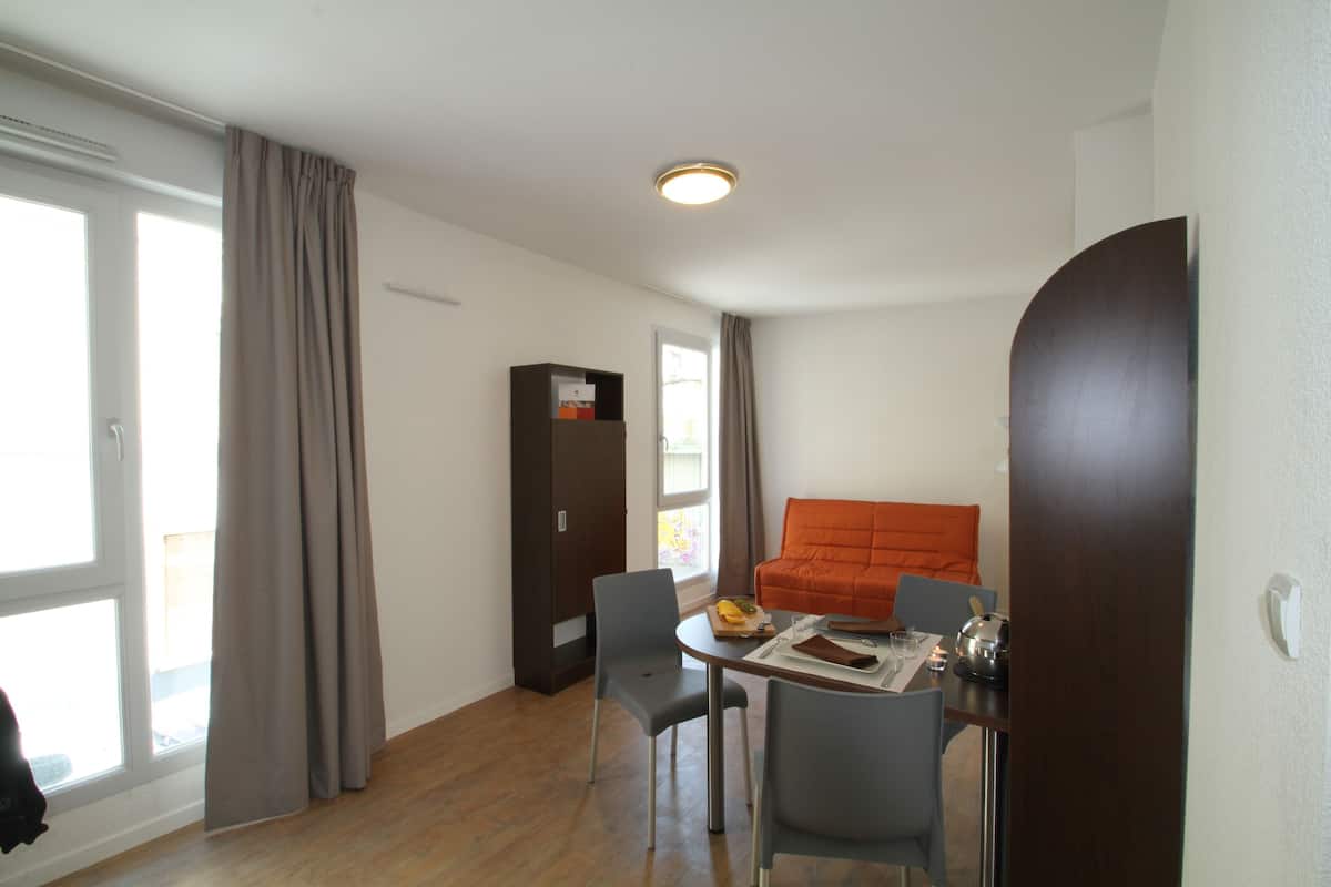 A compact living space with a dining area, a sofa, and a cabinet.