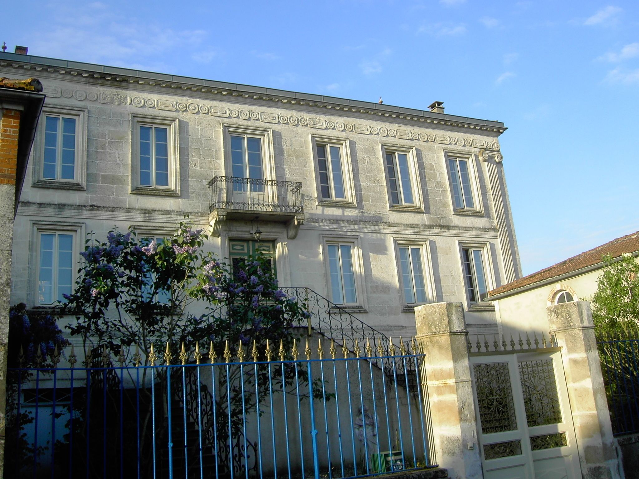 A historic building with a symmetrical facade, multiple windows, and a decorative balcony.