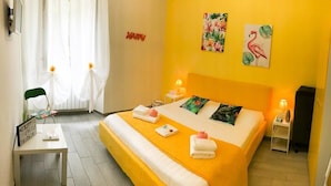 A bright yellow room with a bed, a chair, a table, and a mirror. - Alloggio Turistico Colosseo (Rome)