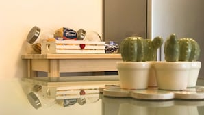 A kitchen counter with a wooden crate containing a can of tomato sauce, a jar of pasta sauce, and a small potted plant. - Alloggio Turistico Colosseo (Rome)