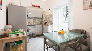 A modern kitchen with a glass dining table, wooden chairs, and a 'Cuisine' sign on the wall. - Alloggio Turistico Colosseo (Rome)