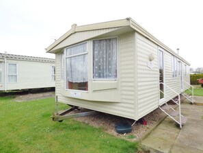 A single mobile home with a front porch, a sliding door, and a small set of steps leading to the entrance. - Caravan Hire at Sunnydale Holiday Park (Louth)