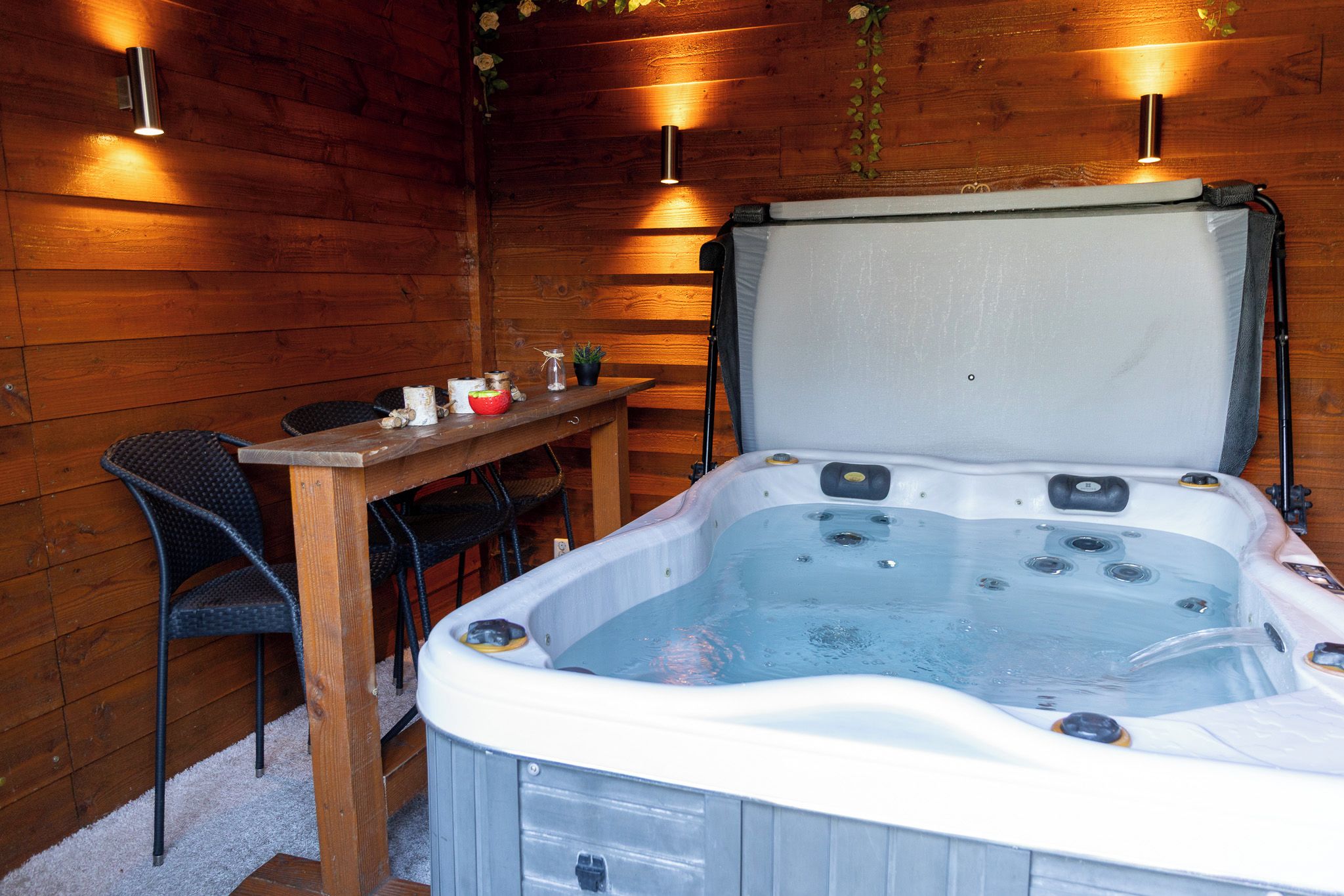 Un bain à remous avec une table et des chaises dans une pièce en bois.
