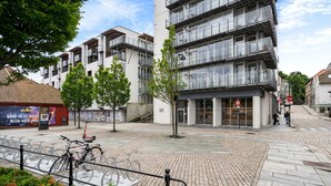 A modern urban square with a paved area, a bicycle rack, and a building with multiple balconies. - Siddis Apartment Sentrum 9 (Stavanger)