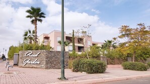Un quartier résidentiel avec une enseigne indiquant « Riad Garden » et un immeuble moderne à deux étages doté de balcons.