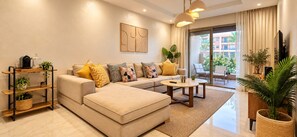 A modern living room with a sofa, coffee table, and a balcony with plants. - RIAD GARDEN LUXURY APARTS by Sabor Voyage (Marrakech)