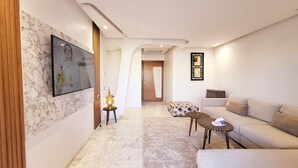 Un salon moderne avec un sol en marbre, un canapé, une table basse et un téléviseur fixé au mur.