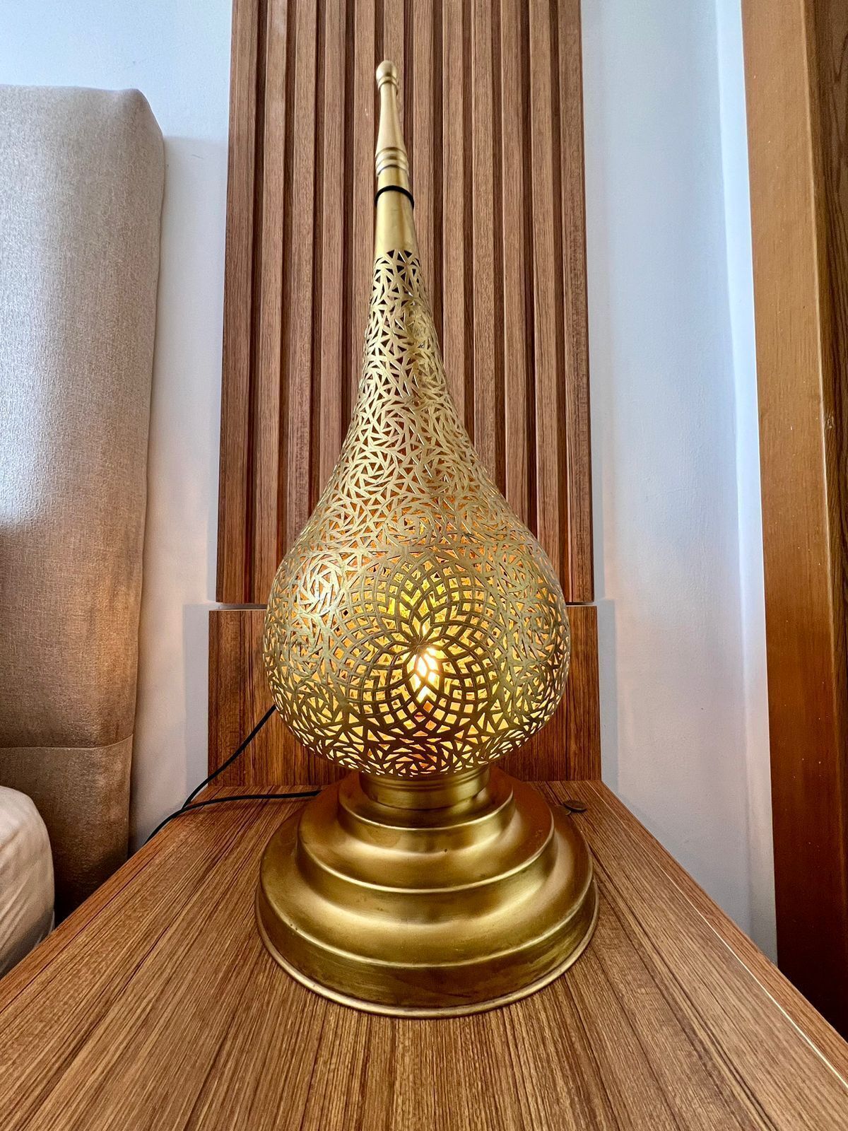 Una lampada da tavolo in ottone con elaborate decorazioni intagliate su un tavolo di legno.