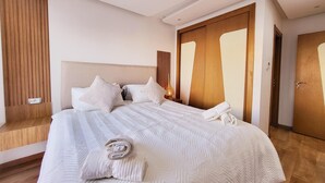 Un lit bien fait, avec une couvre-lit à motifs et des oreillers, une tête de lit en bois et une armoire en bois dotée de portes miroir.