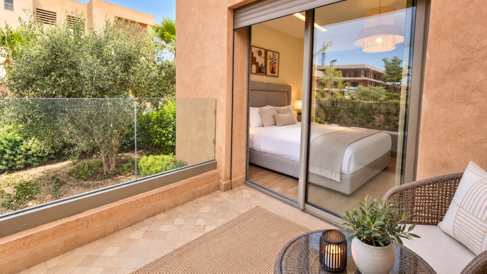 Un balcon avec un lit, une chaise en osier et une plante en pot.