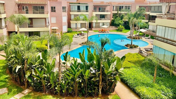 Un hôtel doté d’une piscine centrale, entourée d’une végétation luxuriante et de palmiers.