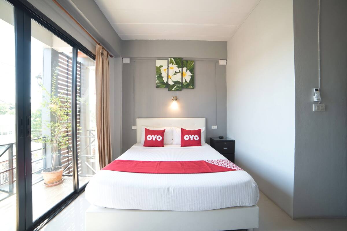 Une chambre d’hôtel avec un lit, une table de chevet, un téléphone fixé au mur et une fenêtre donnant sur l’extérieur.