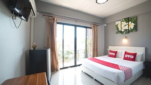 A hotel room with a bed, a desk, a TV, and a balcony with curtains. - OYO 465 Krung Kao Traveller Lodge (Ayutthaya)