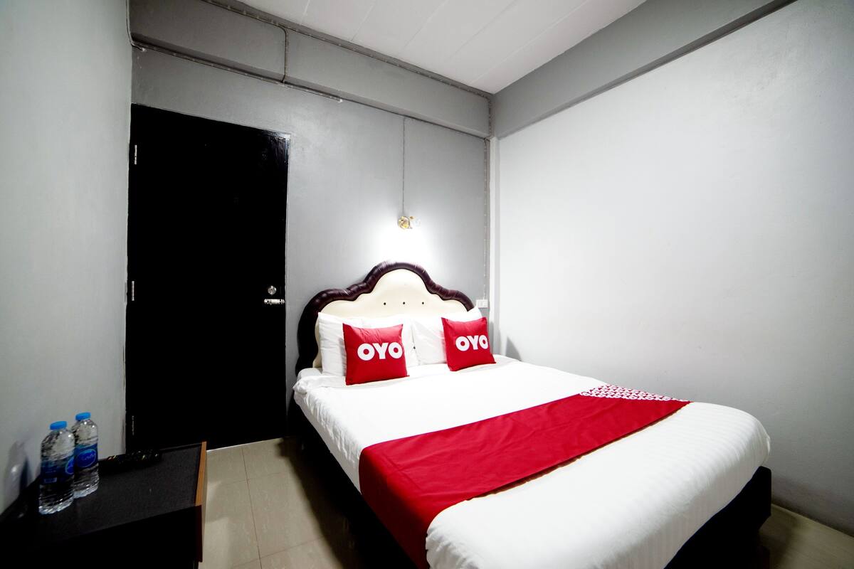 Une chambre d’hôtel avec un lit, une table de chevet et une porte.