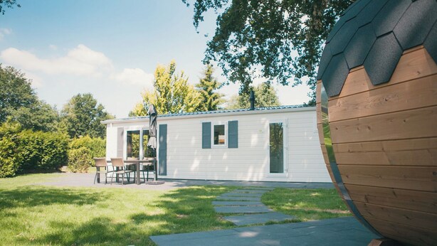 Een stacaravan met een terras, een eettafel en stoelen.