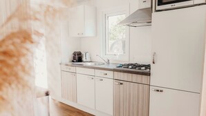 Een moderne keuken met witte kasten, een roestvrijstalen spoelbak, een gasfornuis en een magnetron.