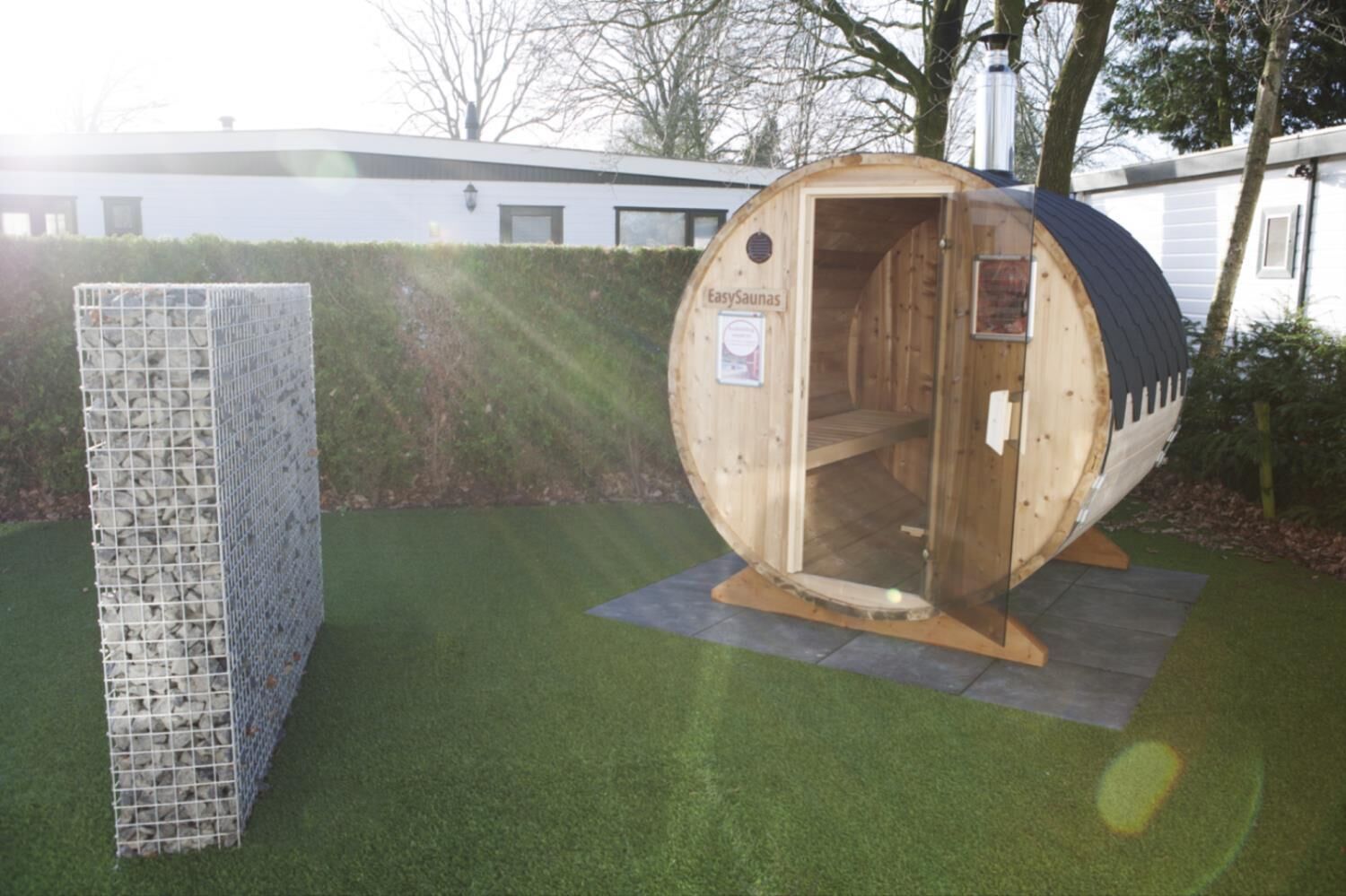 Une structure de sauna avec une façade en bois et une enceinte métallique.