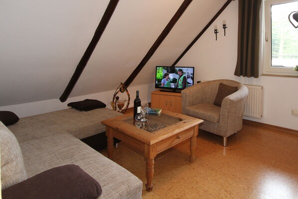 Una sala de estar acogedora con una mesa de centro de madera, dos sofás, un televisor y una ventana con cortinas.
