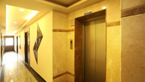 A hallway with an elevator, marble flooring, and a wall-mounted decorative piece. - Balaji Residency (Chennai)