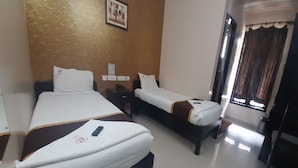A hotel room with two beds, a wooden headboard, a nightstand, a framed picture on the wall, and a window with curtains. - Balaji Residency (Chennai)