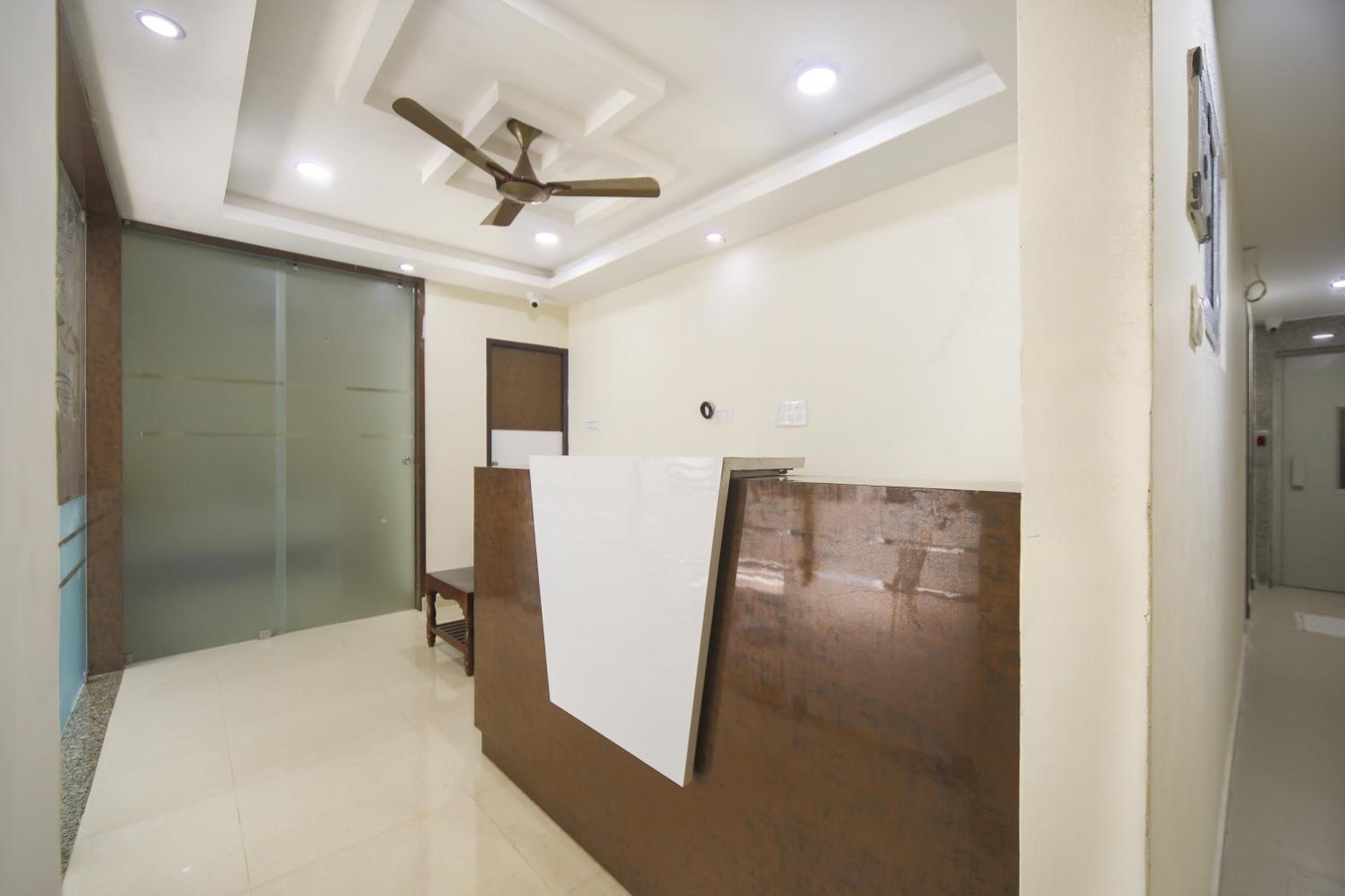A reception area with a glass door, a wooden reception desk, and a ceiling fan.