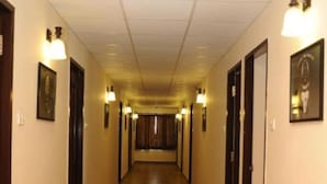 A long, narrow hallway with wooden flooring and doors on both sides, each with a light fixture above. - Balaji Residency (Chennai)