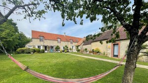 A grassy yard with a hammock, a stone building with a red roof, and a tree. - Le Bourg d'Aunou (Aunou-sur-Orne)