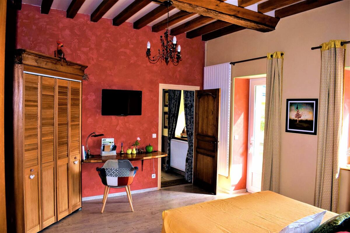 Een kamer met een bed, een houten kledingkast, een bureau met stoel en een televisie.