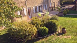 A stone house with a tiled roof, a wooden deck, and a well-maintained garden. - Le Bourg d'Aunou (Aunou-sur-Orne)