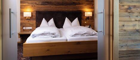 A double bed with white linens, two bedside lamps, and a wooden headboard.