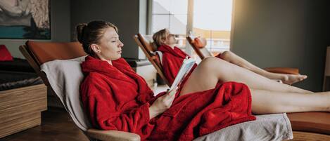 A room with two reclining chairs, one occupied by a person reading a book.