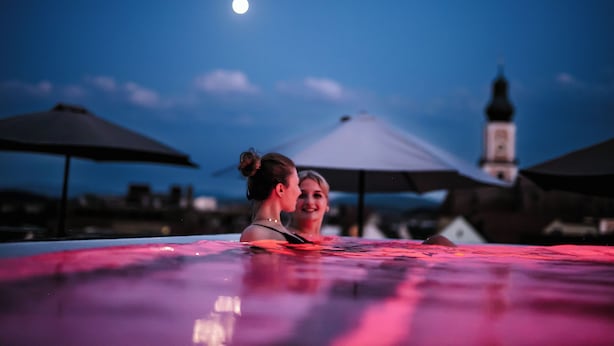A couple in a pool with a moon in the background.