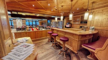 A wooden interior with a bar area, bar stools, and seating.