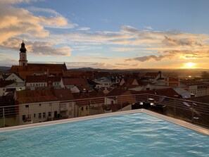 A swimming pool with a view of a town and a church tower.