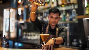 A bartender pouring a drink into a martini glass.