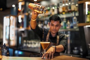 Un cantinero sirviendo una bebida en una copa de martini.