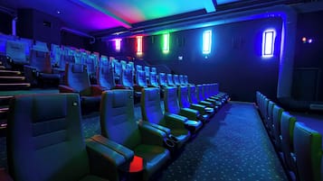 Un cine con filas de asientos, cada uno con una mesita pequeña y un portavasos.