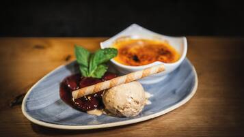 Un plato de postre con helado, compota de bayas y una galleta.