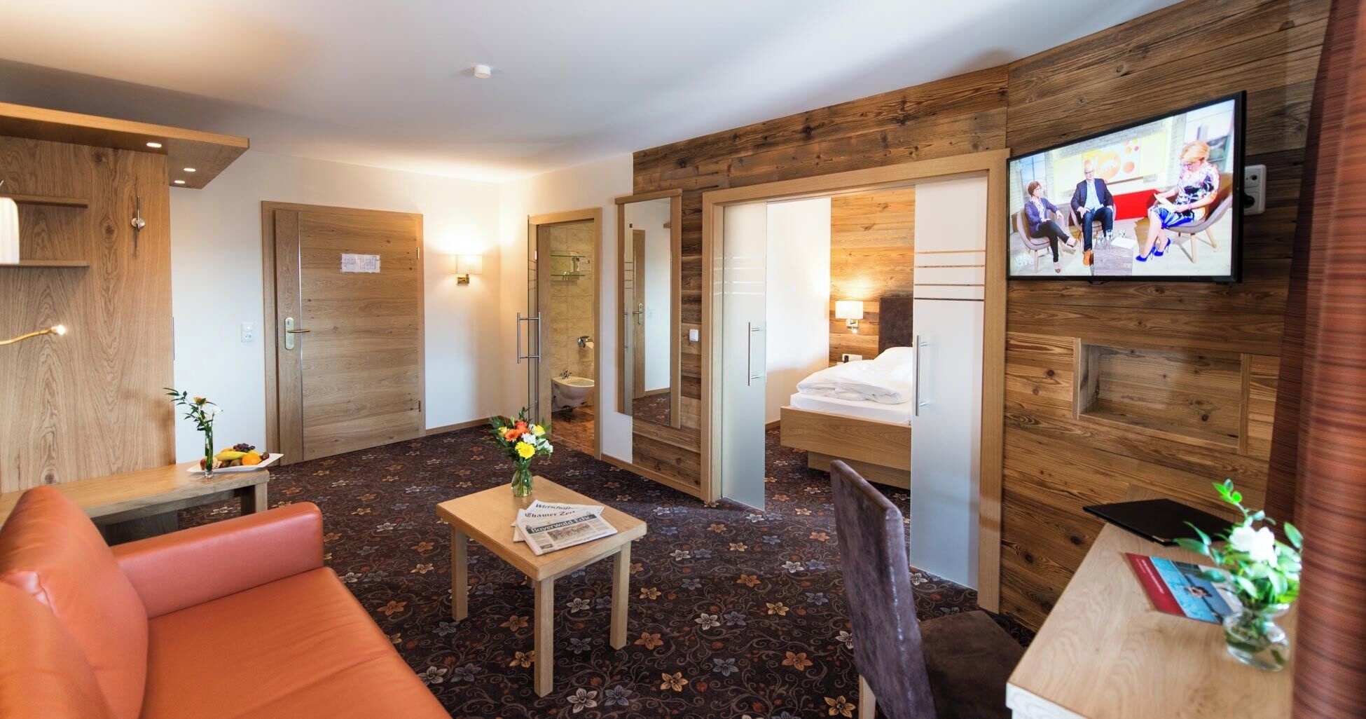 Una habitación de hotel con cama, escritorio, televisor, sofá y baño.