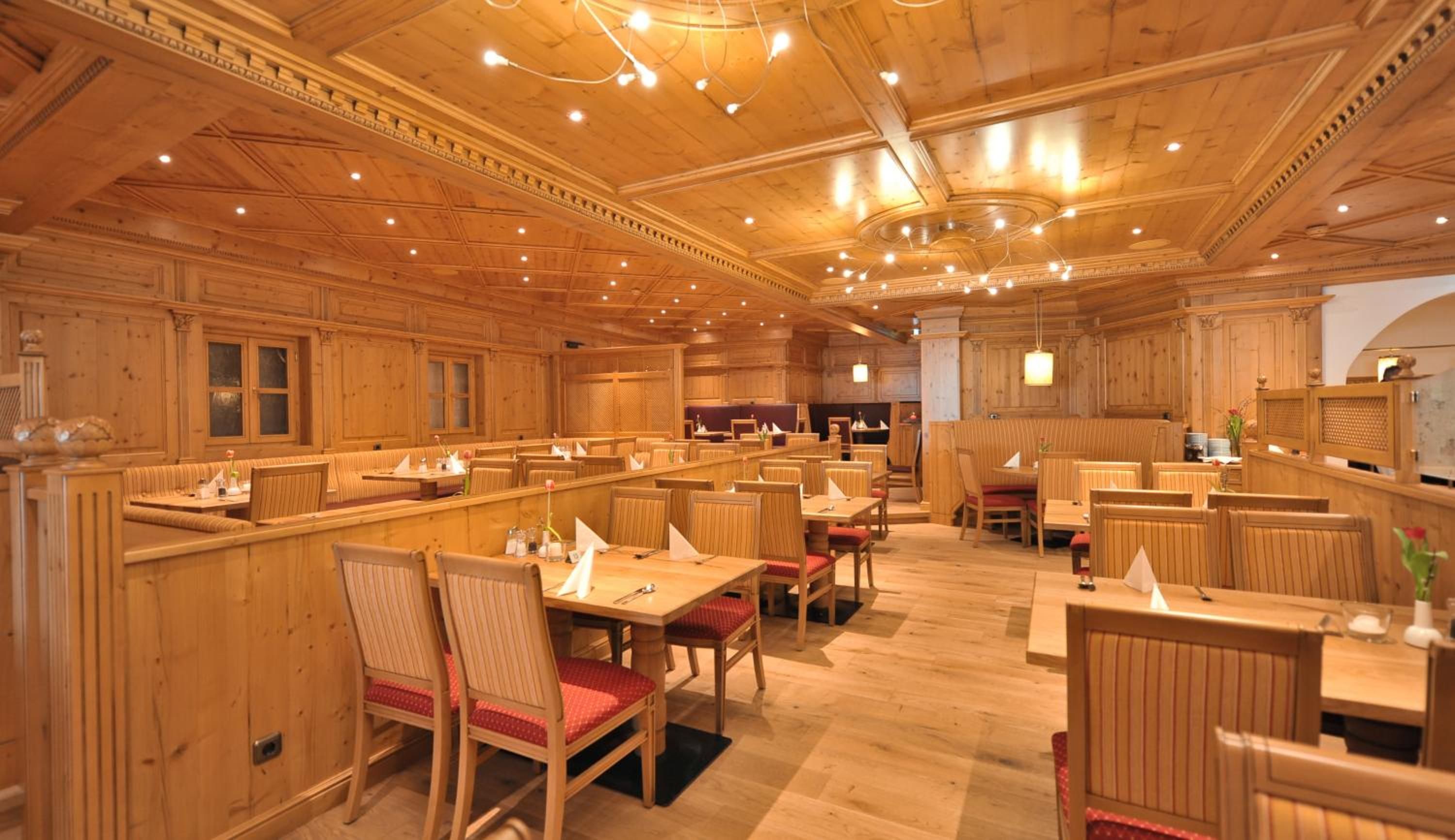 A restaurant with wooden paneling, multiple dining tables and booths, and a high ceiling with recessed lighting.