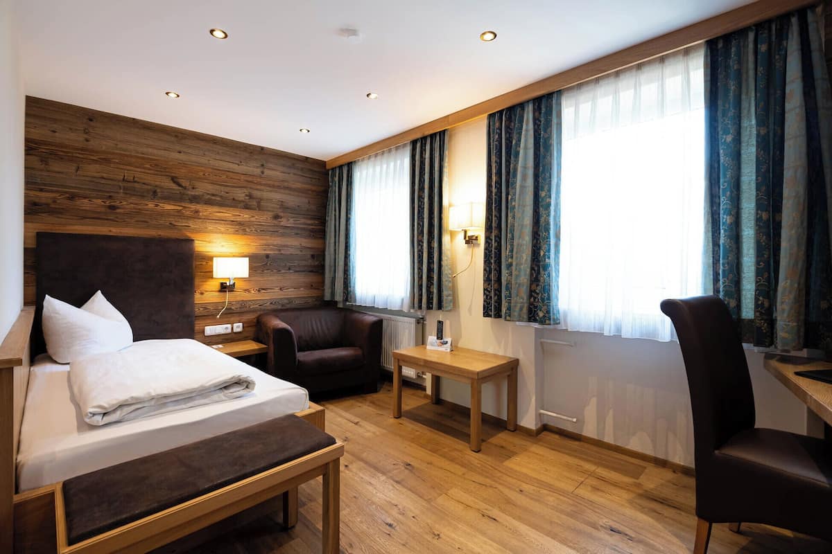 A hotel room with a bed, a desk, a chair, and a sofa.