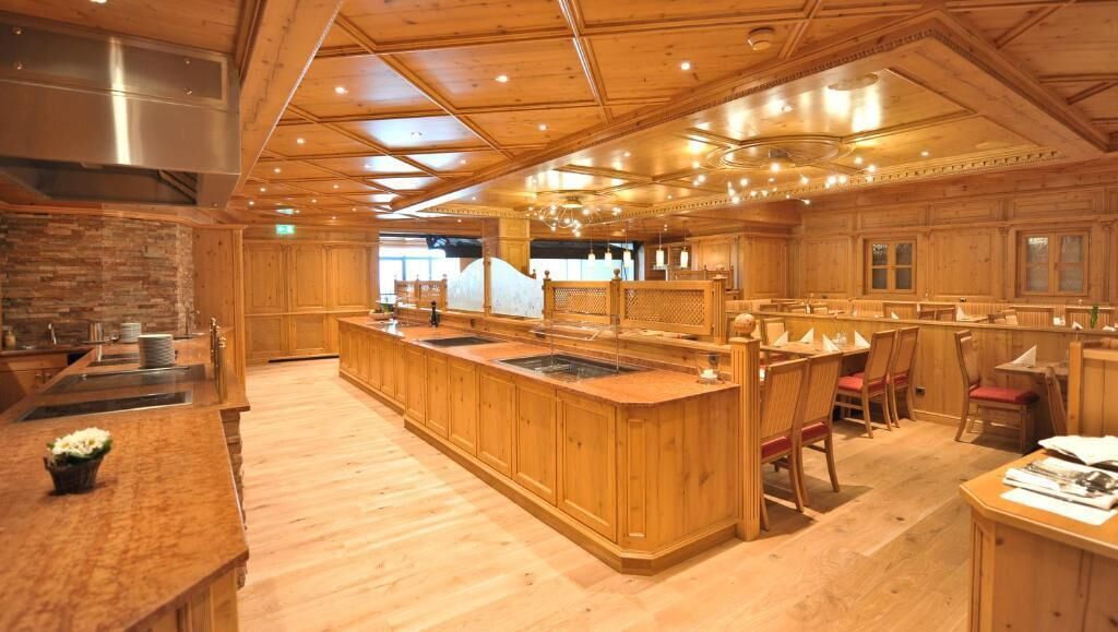 Un restaurante espacioso con interiores de madera, una zona de bar central y diversas opciones de asientos.